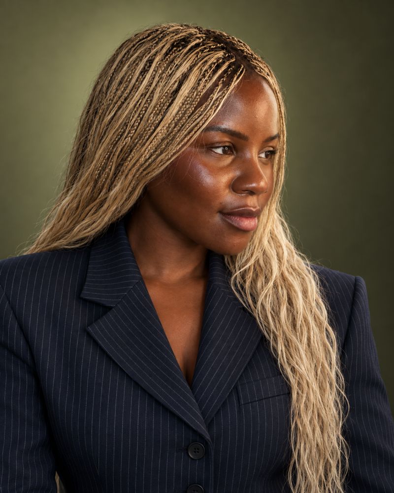 Stephanie Anani in a navy pinstripe blazer with blonde braids, looking to the side.